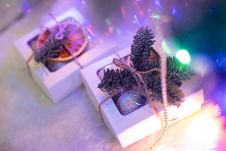 White square boxes decorated with pine branches and neon lights around, Christmas gifts, Handmade decoration, family holidaysの写真素材