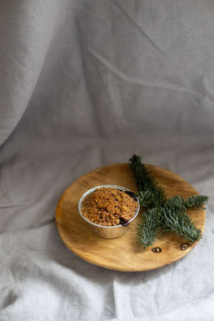 Crumble cake in a small cup placed on wooden plate decorated with fir branchの写真素材
