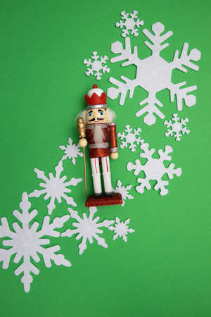 A nutcracker on green backdrop and bunch of snowflakesの写真素材