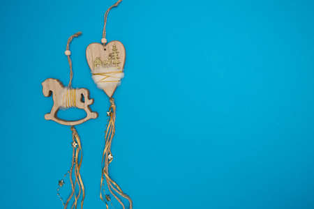 Wooden horse and heart Christmas decorations with ribbons and beads laying on blue backgroundの写真素材