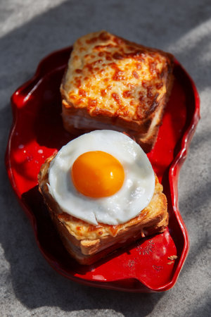 Two iconic French sandwiches: Croque Madame and Croque Monsieur, oozing with melted cheese and...