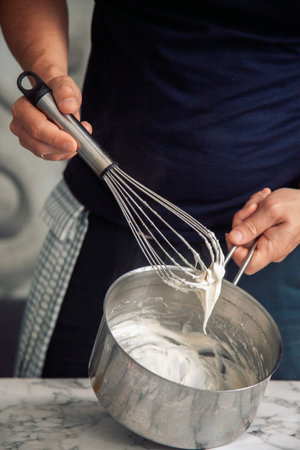 A skilled chef whisking a creamy white bÃ©chamel sauce, showcasing culinary expertise and precision.の写真素材