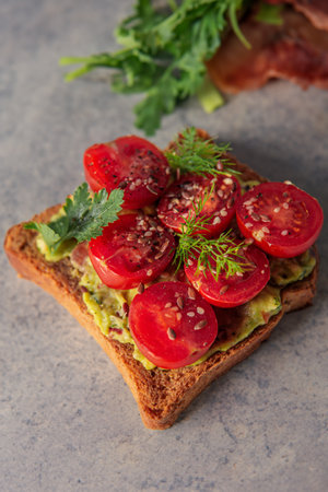 Deliciously topped toast with creamy guacamole and vibrant sliced cherry tomatoes for a refreshing bite.の写真素材
