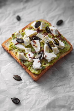 Creamy guacamole topped with tangy feta cheese and crunchy pumpkin seeds for a delightful flavor combination.の写真素材