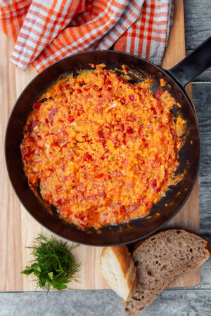 A colorful omelette with tomatoes cooking in a frying pan, sizzling and ready to serve.の写真素材