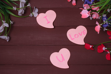 Card with Message Love You on the Letter on wooden background flowers