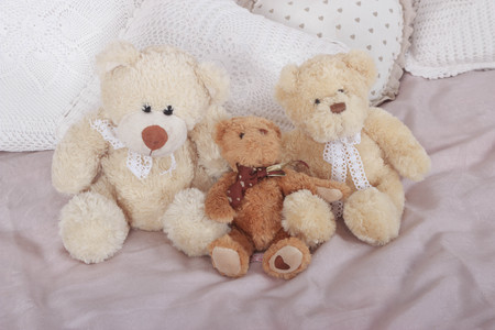 a group of cute teddy bears sitting together on bedの写真素材
