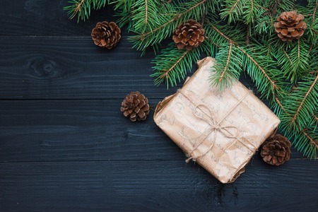 Wrapping rustic eco Christmas packages with brown paper, string and natural fir branches on dark background. Flat lay, free space.の写真素材