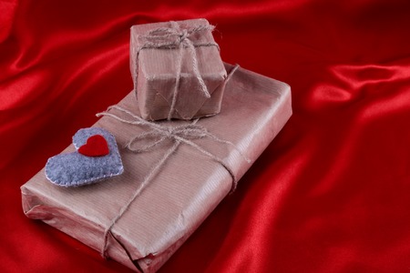 Two presents with felt heart on red backgroundの写真素材