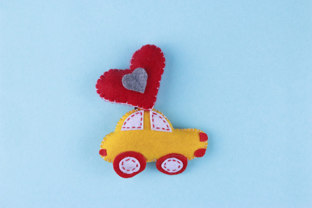 felt toy car with a red heart balloon against a blue background. Valentines Day or love concept.の写真素材