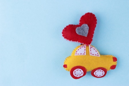 felt toy car with a red heart balloon against a blue background. Valentines Day or love concept.の写真素材