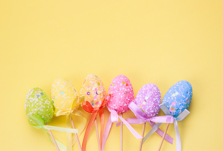 Easter holiday background. Pastel coloured decorated easter eggs on a bright yellow background