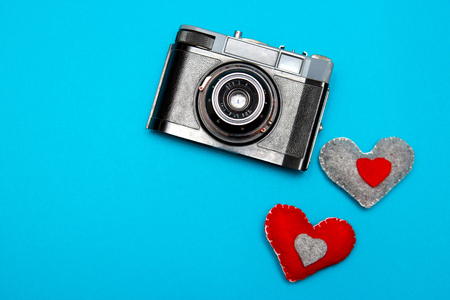vintage camera on blue background with two felt hearts.