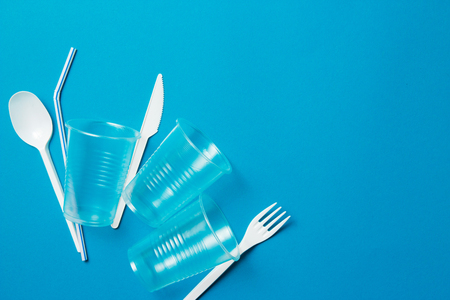 White single-use plastic knife, spoon, fork and plastic drink straws on a blue background. Say no to single use plastic. Environmental, pollution conceptの写真素材