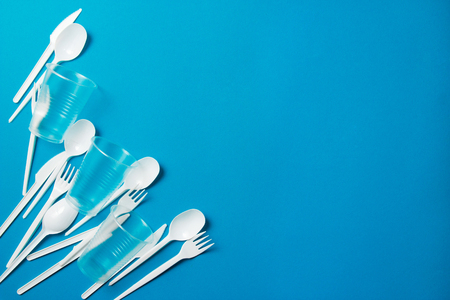 White single-use plastic knives, spoons, forks on a blue background. Say no to single use plastic. Environmental, pollution conceptの写真素材