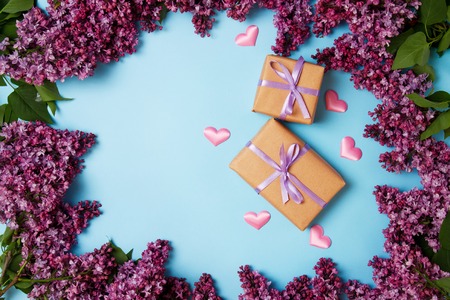 Frame of lilac flowers with two gift boxes on a blue background. Top view. Mothers day.の写真素材