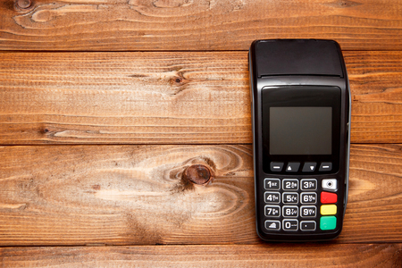 Payment terminal, compact POS terminal on wooden background top view copy spaceの写真素材