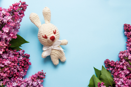 Lilac flowers with knitting toy rabbit on blue background. Top view, flat lay, copy space.の写真素材