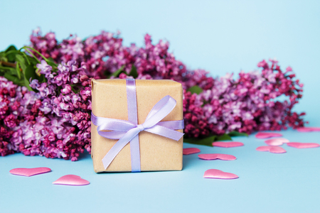 Frame of lilac flowers with gift box on a blue background. Mothers day.の写真素材