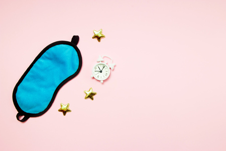 Blue sleeping eye mask, alarm clock on pink background. Do not disturb me, let me sleep. Rest, good night, siesta, insomnia, relaxation, tired, travel conceptの写真素材