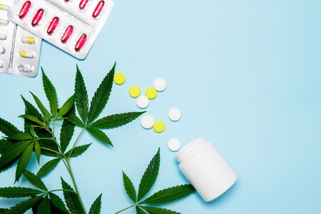 Marijuana leaf with medical pills on blue background. The concept of legalization of marijuana. Top view.の写真素材