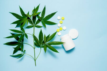 Marijuana leaf with medical pills on blue background. The concept of legalization of marijuanaの写真素材