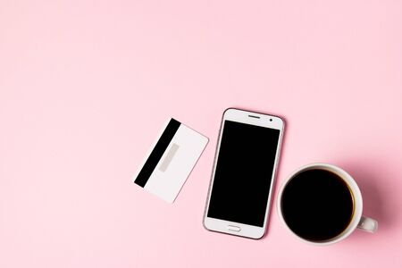Smartphone, cup of coffee and credit card on a pink background. Top view, business concept.の写真素材