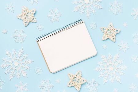 Clean notebook for goals or christmas shop list and resolutions on blue background with decorative stars and snowflakes. Top view, flat lay, copy space.の写真素材