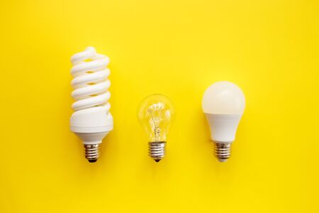 LED lamp, fluorescent and incandescent on a yellow background. Top view, flat lay. Choice concept.