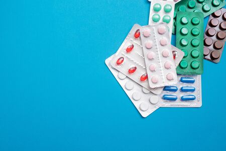 Pills in blister on blue background. Flat lay, copy space, top view. Health concept