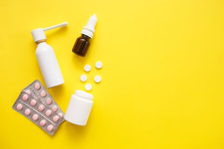 Treatment of colds and flu. Various medicines, sprays from a stuffy nose and a pain in a throat and pills on a yellow background. Copy space. Medicine flat layの写真素材