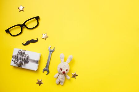 Father's day concept card with man's work tool on yellow background and gift box, mustache and glasses. Top view, flat lay, copy spaceの写真素材
