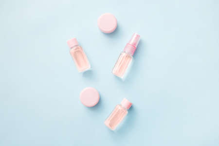 Flat lay of flowers and cosmetics products essential oil: toner, serum, essence, moisturizer and others on blue background, top view, banner. Facial Skin care beautyの写真素材