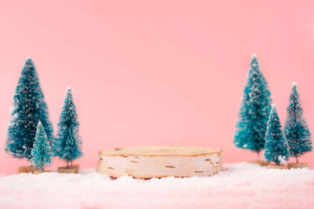 Mock up with wooden podium from a circle of wood on trendy pastel pink background with christmas decoration tree. Place for christmas product presentation.の写真素材