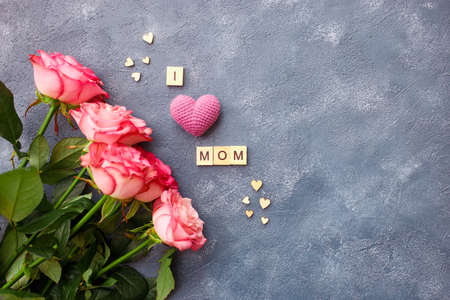 Mothers day greeting card concept. Bouquet pink roses with letters in word i love mom on blue...
