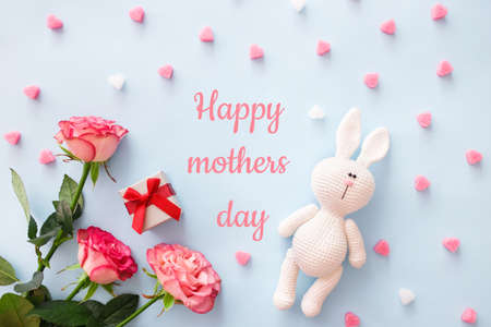 Greeting card concept. Bouquet pink roses, amigurumi bunny with letters in word Happy Mothers Day...