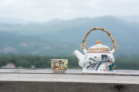 Tea pot and cup on wood table and mountain viewの写真素材