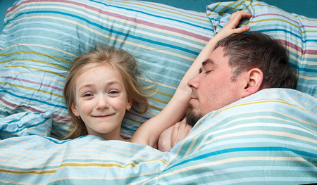 Little girl 5 years sleeping cuddling with daddy in bedの写真素材