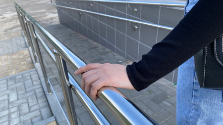 Woman hand holds on to railing on the street while going down on ramp
