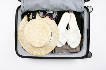 Open suitcase packed for traveling. Hat, glasses, sandals.の写真素材