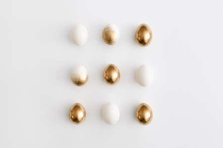 Golden eggs on a white background. Minimal easter concept.の写真素材