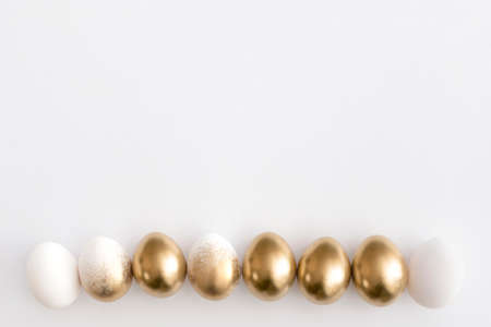 Golden eggs on a white background. Minimal easter concept.の写真素材