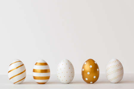 Golden eggs on a white background. Minimal easter concept.の写真素材