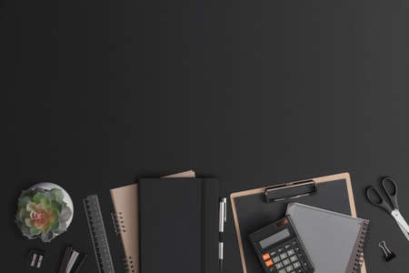 Black leather office table with calculator, notebook and green plant. Top view with copy space. Flat...