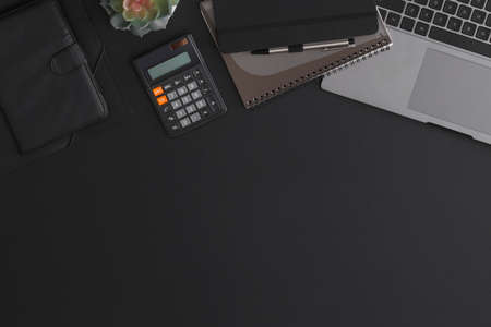 Black leather office table with calculator, notebook and green plant. Top view with copy spaceの写真素材