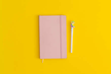 Notebook and pen on yellow background. Top view. Flat lay. Back to school concept.