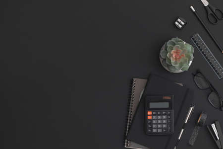 Black leather office table with calculator, notebook, stationery and green plant. Top view with copy space. Flat lay composition.の写真素材
