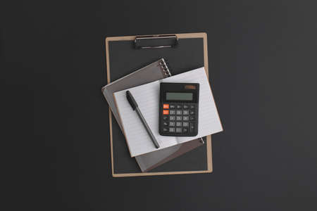 Calculator, notebook, pen on black leather background.の写真素材