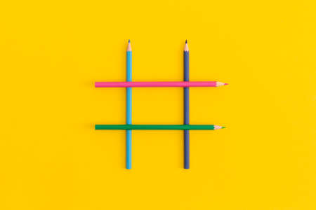 Hashtags sign made of colored pencils on yellow background