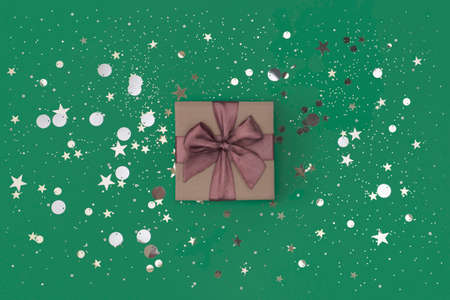 Gift box with purple bow on green background with confettiの写真素材
